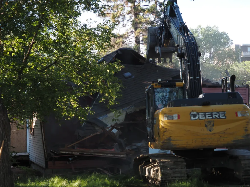 an excavator tearing down a small house