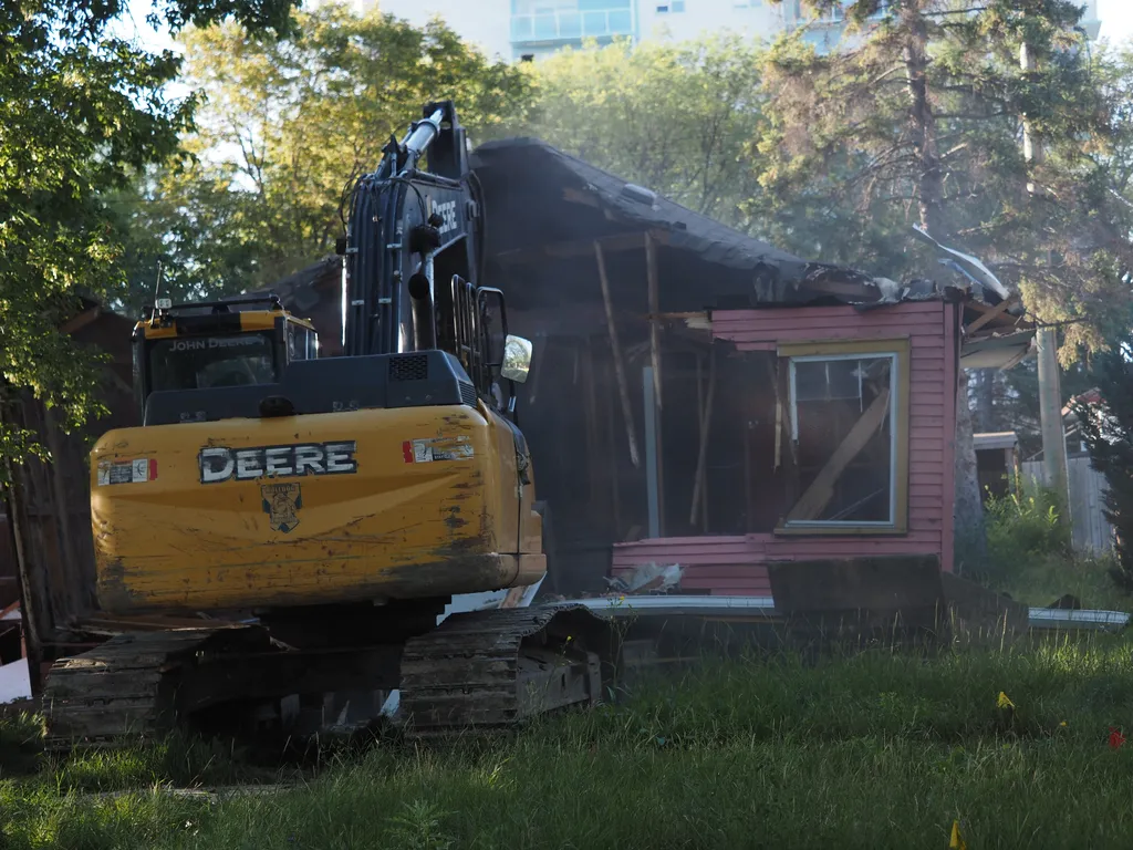 an excavator tearing down a small house