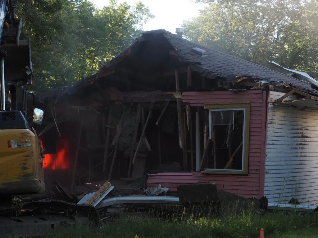 an excavator tearing down a small house