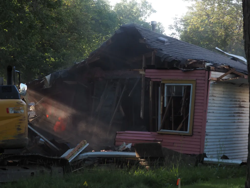 an excavator tearing down a small house