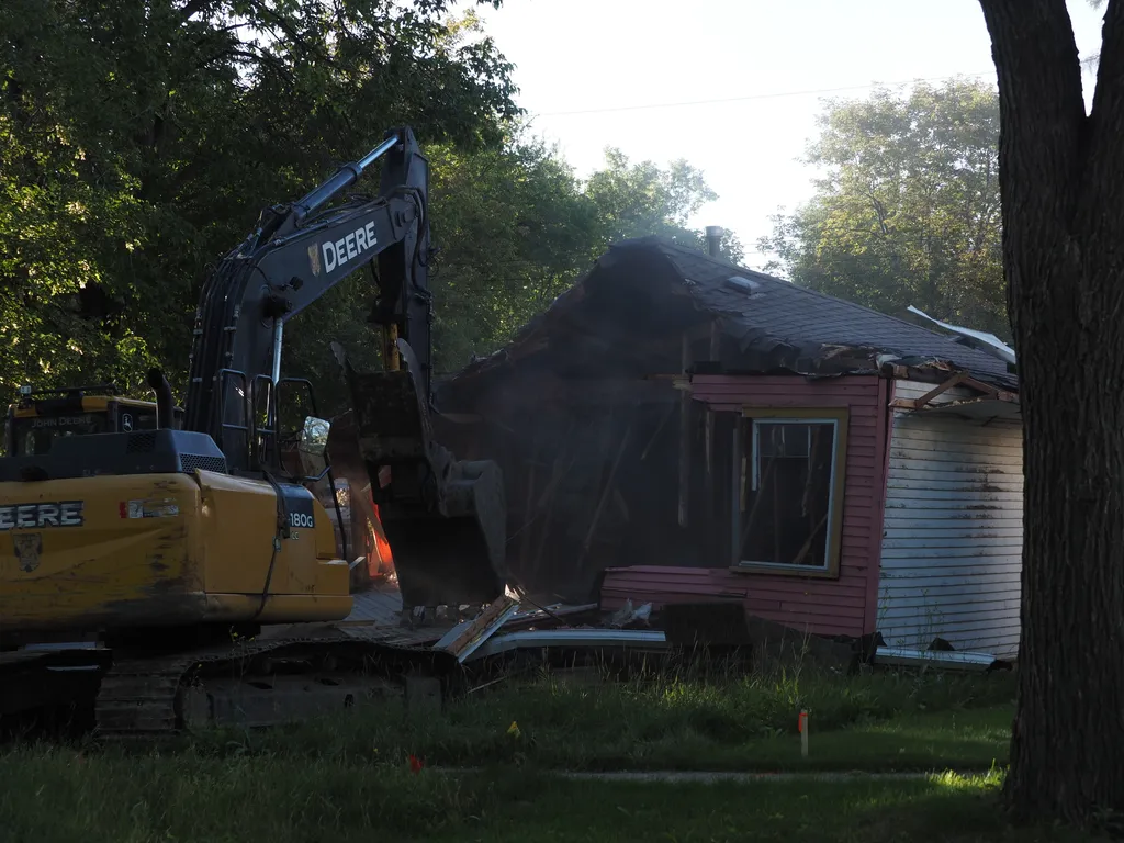 an excavator tearing down a small house