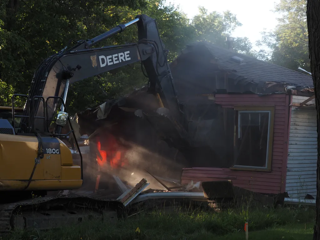 an excavator tearing down a small house