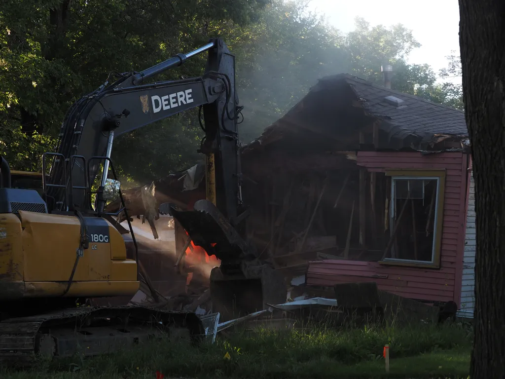 an excavator tearing down a small house