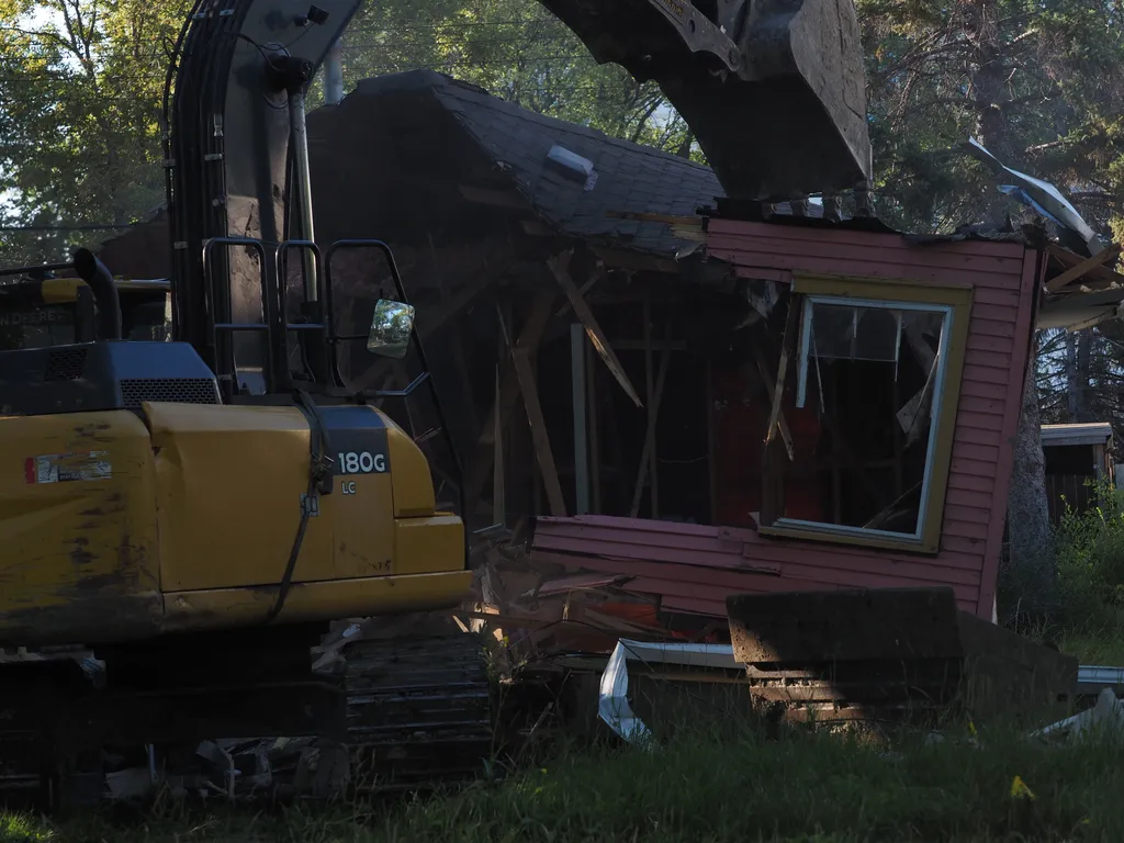 an excavator tearing down a small house