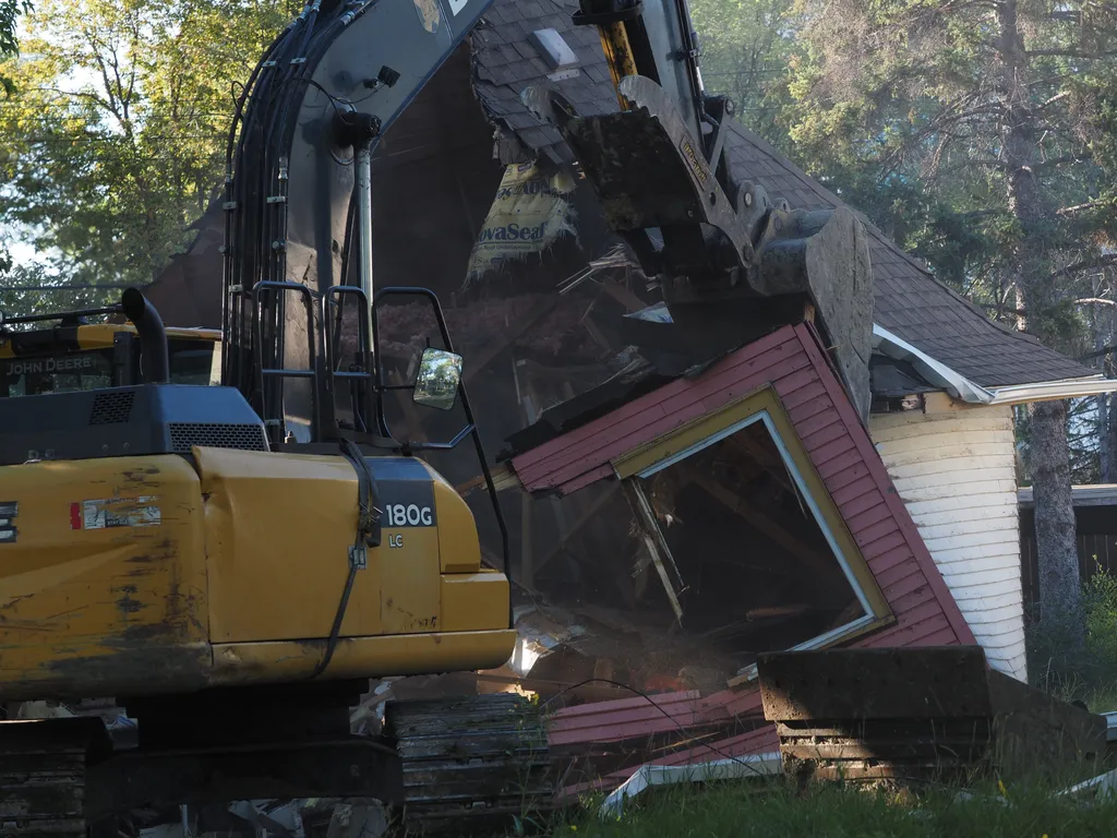 an excavator tearing down a small house