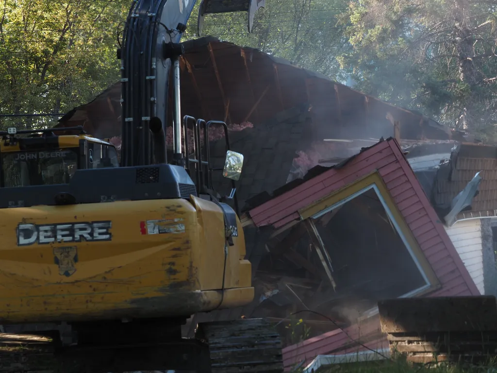 an excavator tearing down a small house