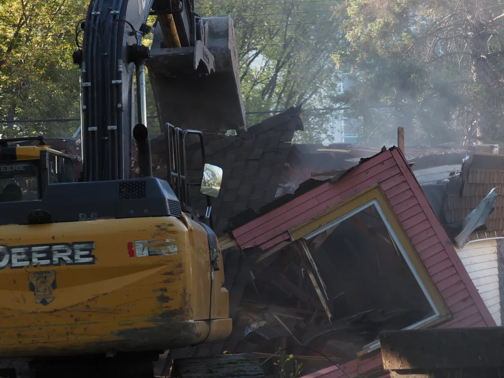 an excavator tearing down a small house