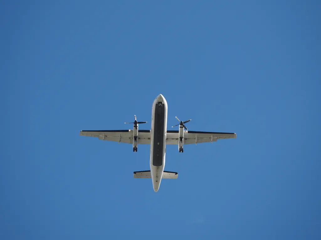 a large propeller plain with its landing gear out viewed from below