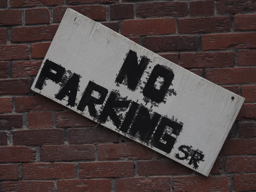 a no parking sign with bleeding text falling from a brick wall