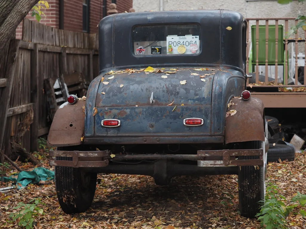 a rusting antique car viewed from behind