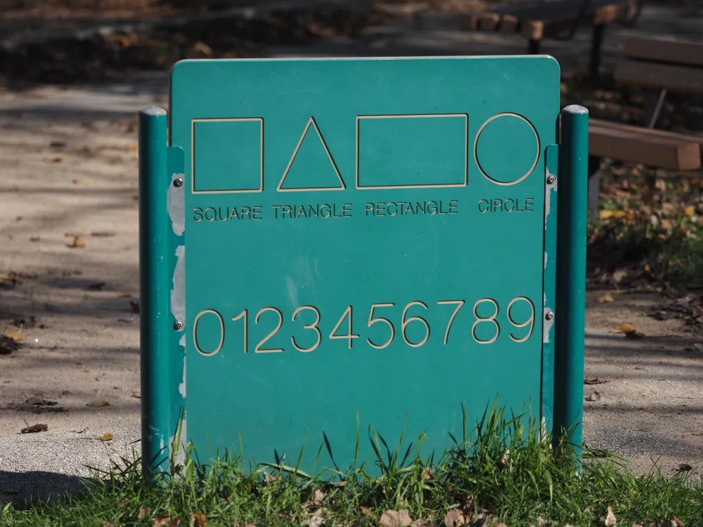 a sign with shapes and numbers in a children's playground