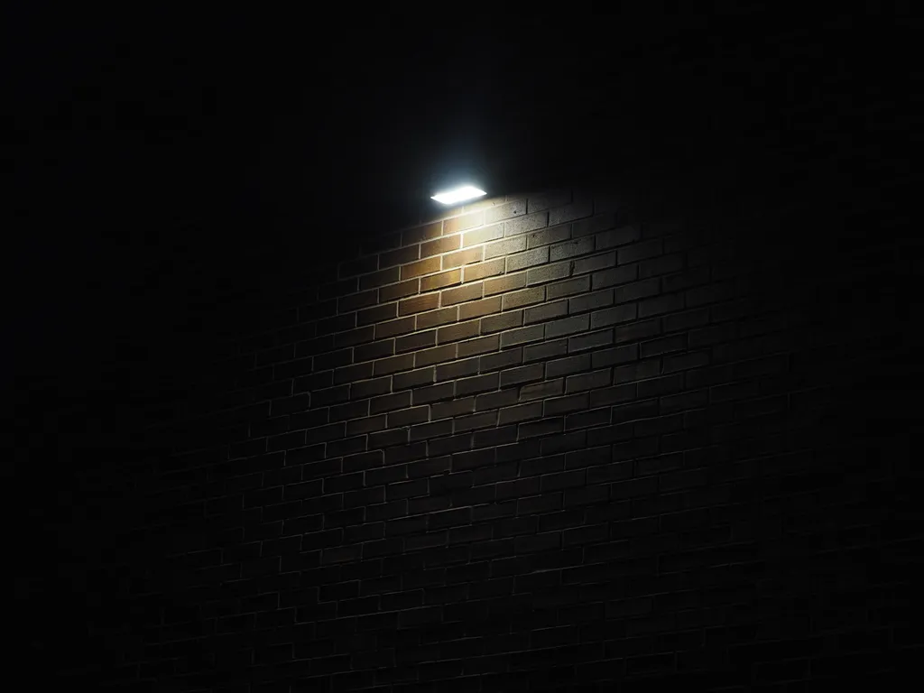 a light illuminating a brick wall