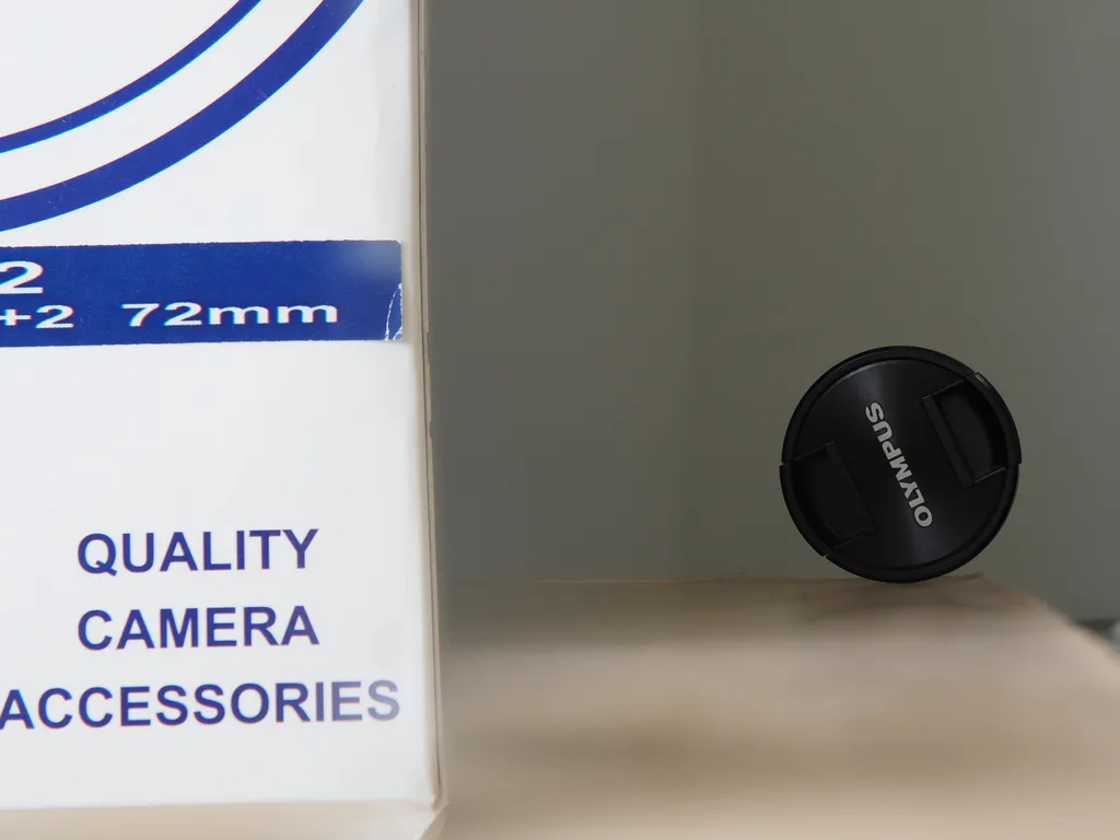 a box with a lens cap considerably behind it. text on both remain clearly legible