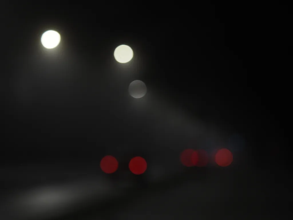 cars driving down a street on a foggy night