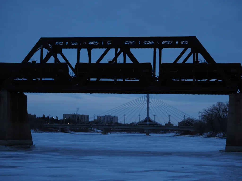 a train parked on a bridge over a frozen river