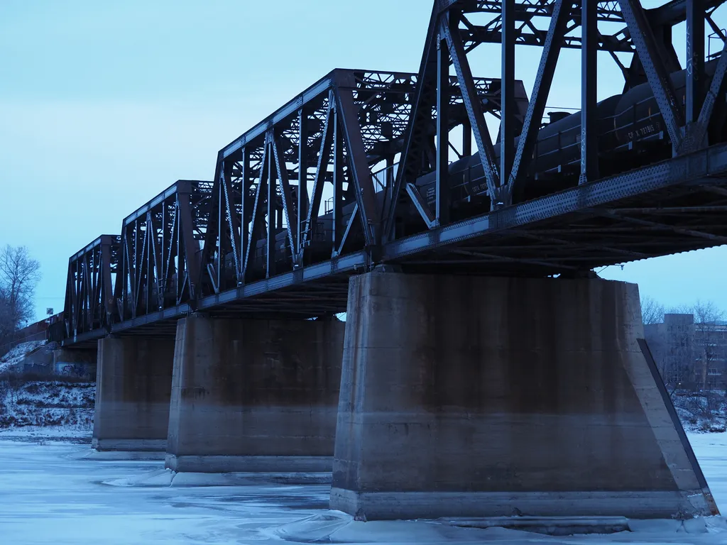 a train parked on a bridge over a frozen river