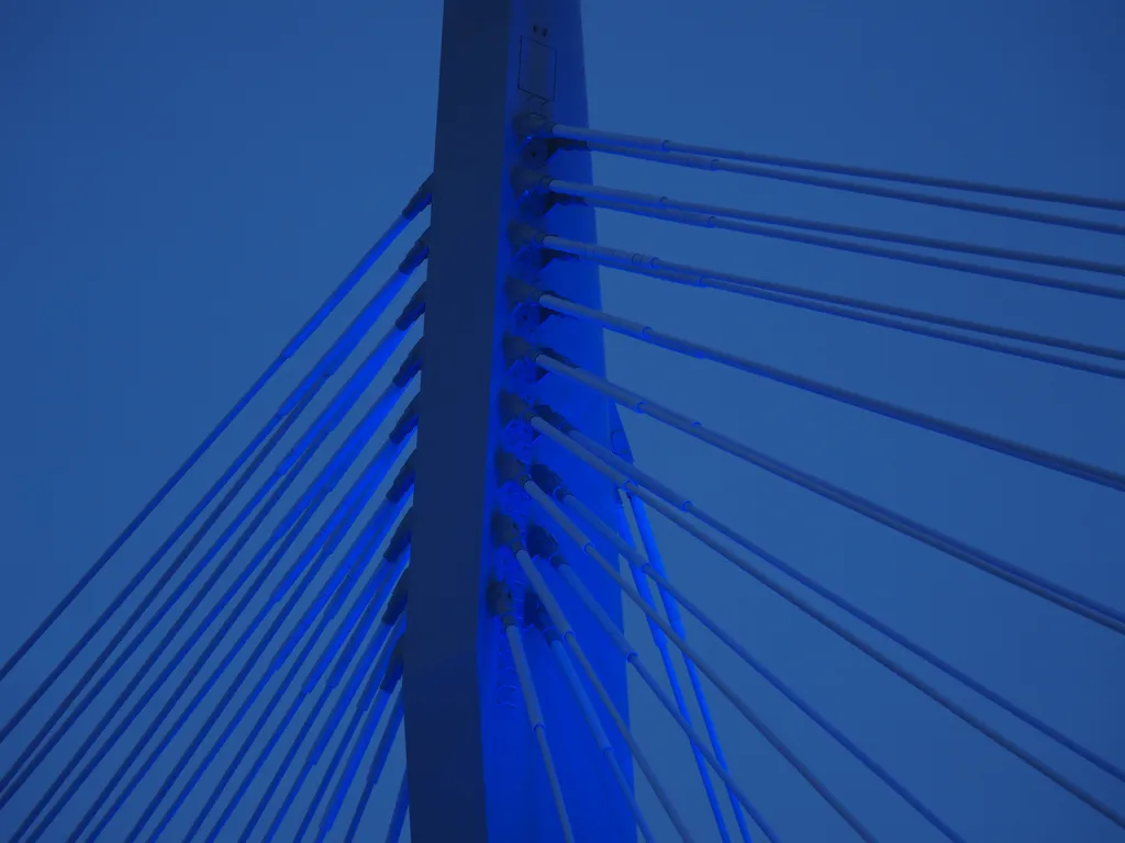 the tip of a suspension bridge lit in blue lights