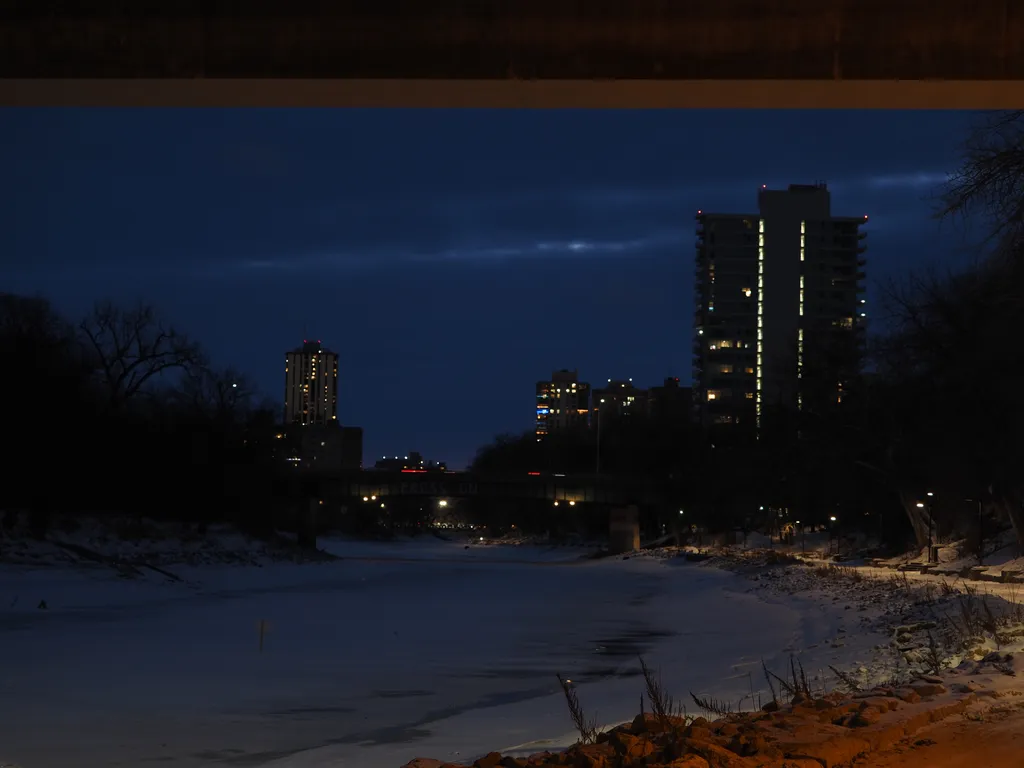 tall apartment buildings at night by a frozen river