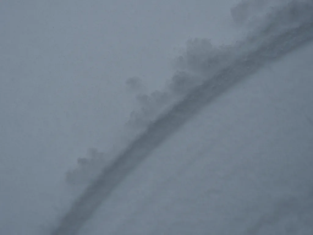 an arc carved in fresh snow by an opening door