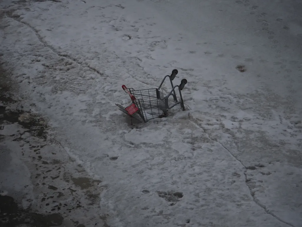 a shopping cart sticking half out of a frozen river