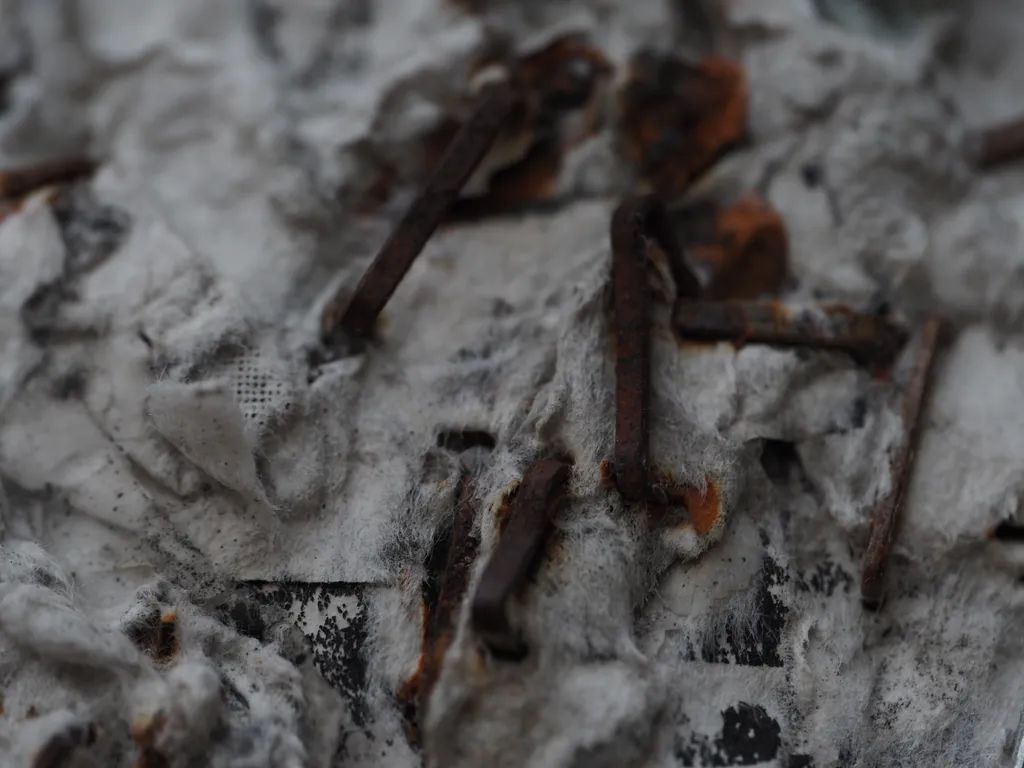 scraps of sopping paper held to a utility pole with rusty staples