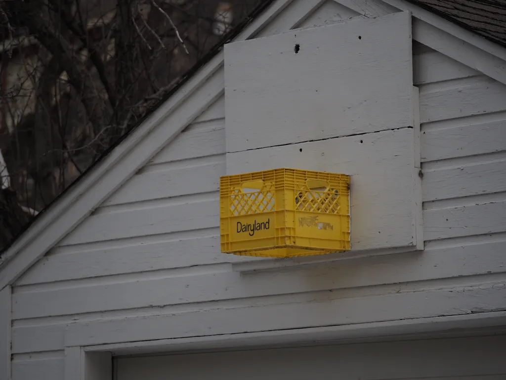 a basketball hoop made out of a square plastic milk crate with its bottom cut out attached to painted plywood