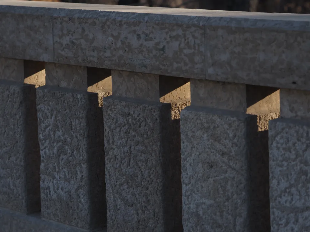 light filtering through the stone railing of a bridge