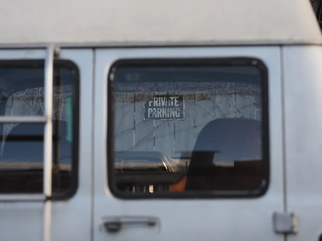 a private parking sign as viewed through the window of a van