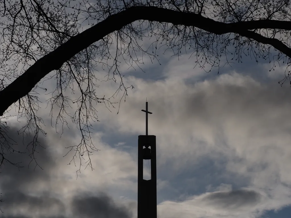 the spire of a church silhouetted against a cloudy sky