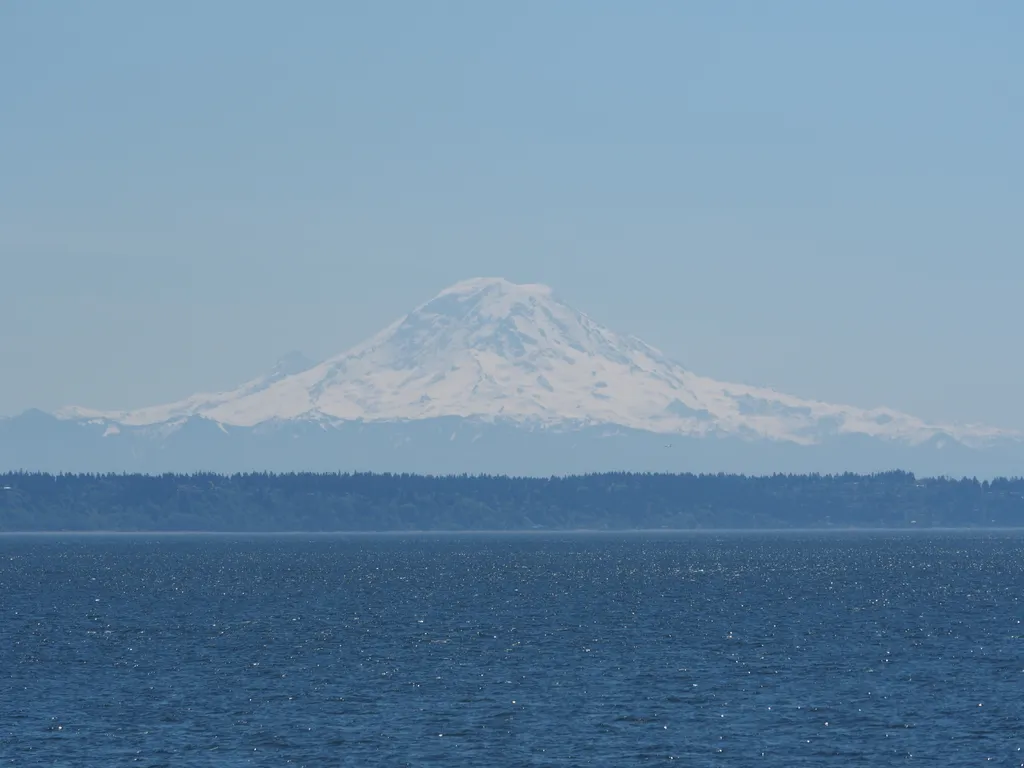 a large snow-capped mountain viewed from the water on a clear day