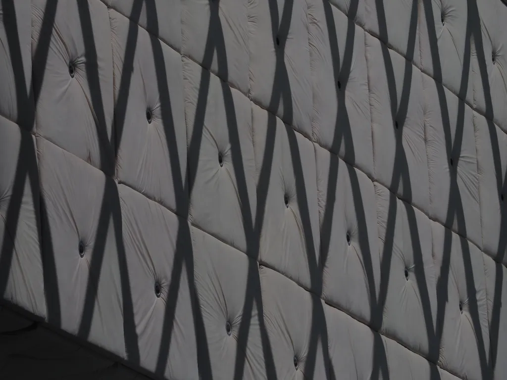 the diamond frames of a window casting shadows on a cusioned wall