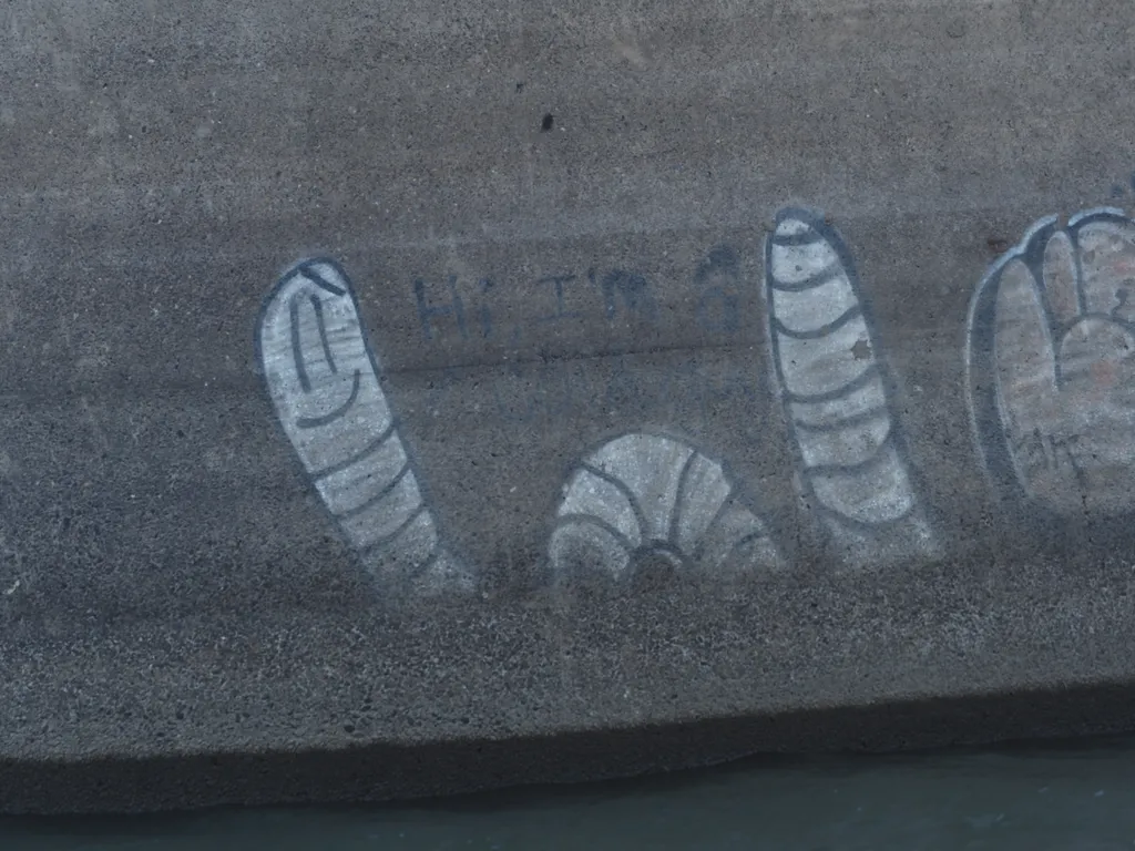 a worm spraypainted onto the concrete pillar of a bridge