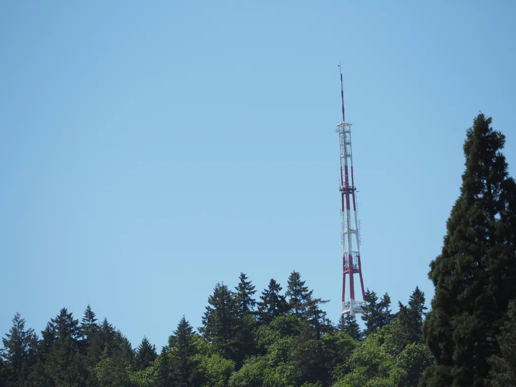 a radio tower on top of a forrested hill