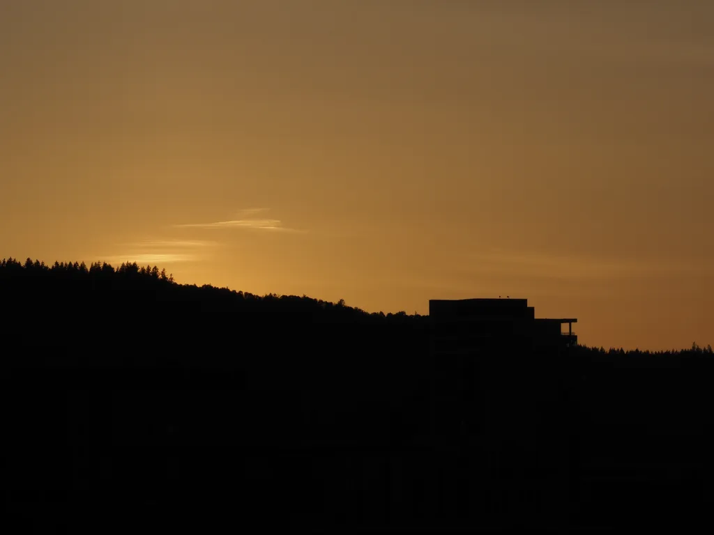 the sun setting behind a hill