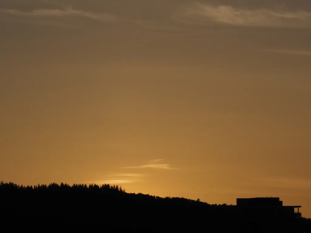 the sun setting behind a hill