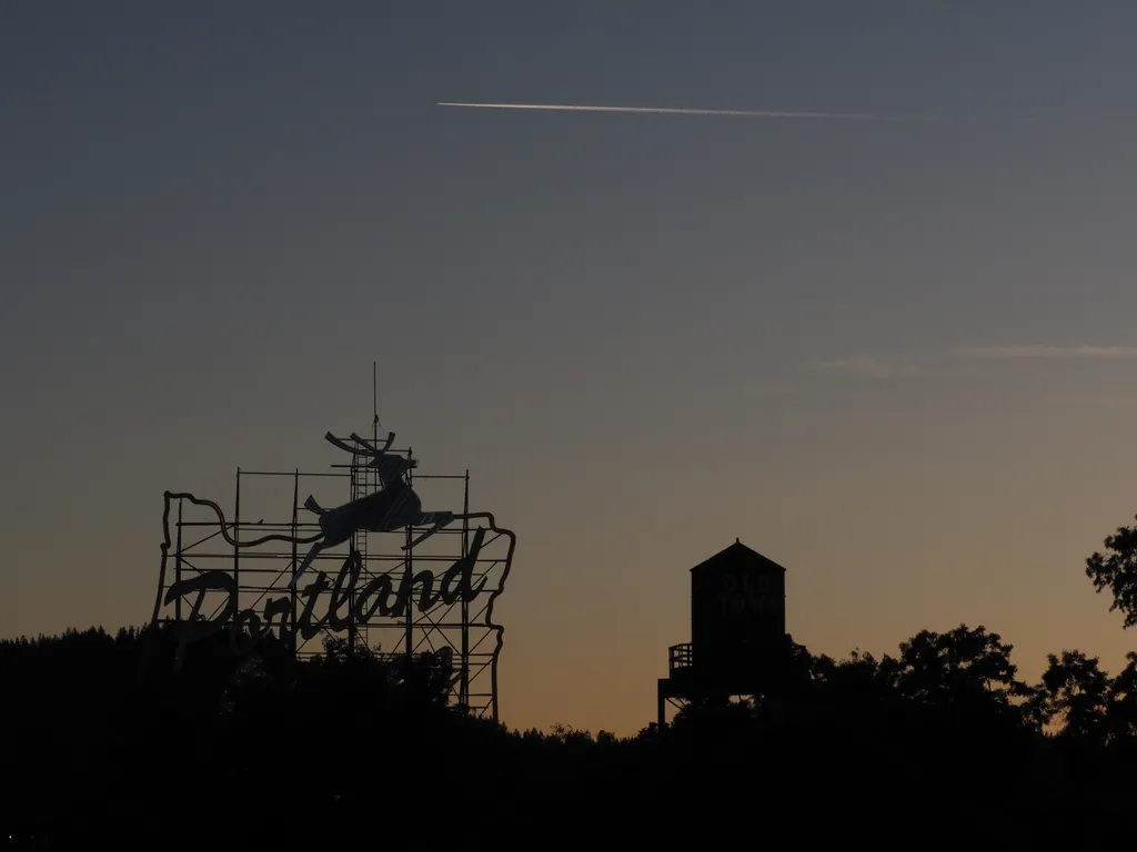 the sun setting behind a portland sign