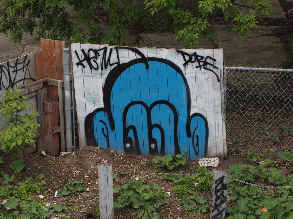 a bald blue head painted on a fence