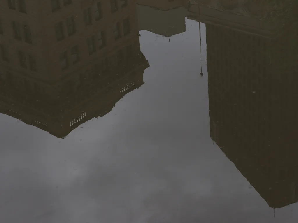 old brick skyscrapers reflected in a puddle