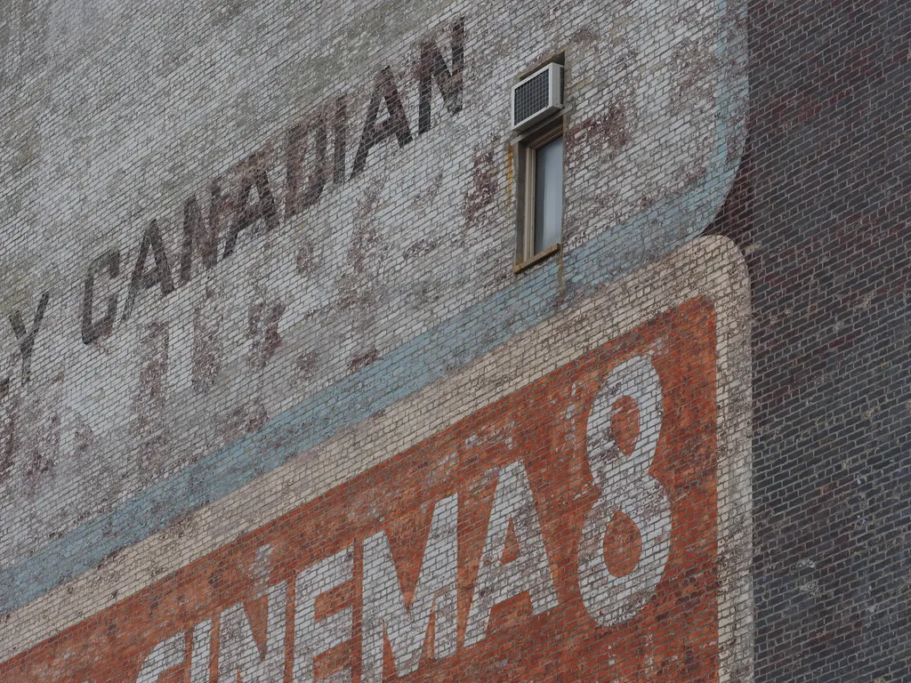 a fading ad for a cinema on a brick wall