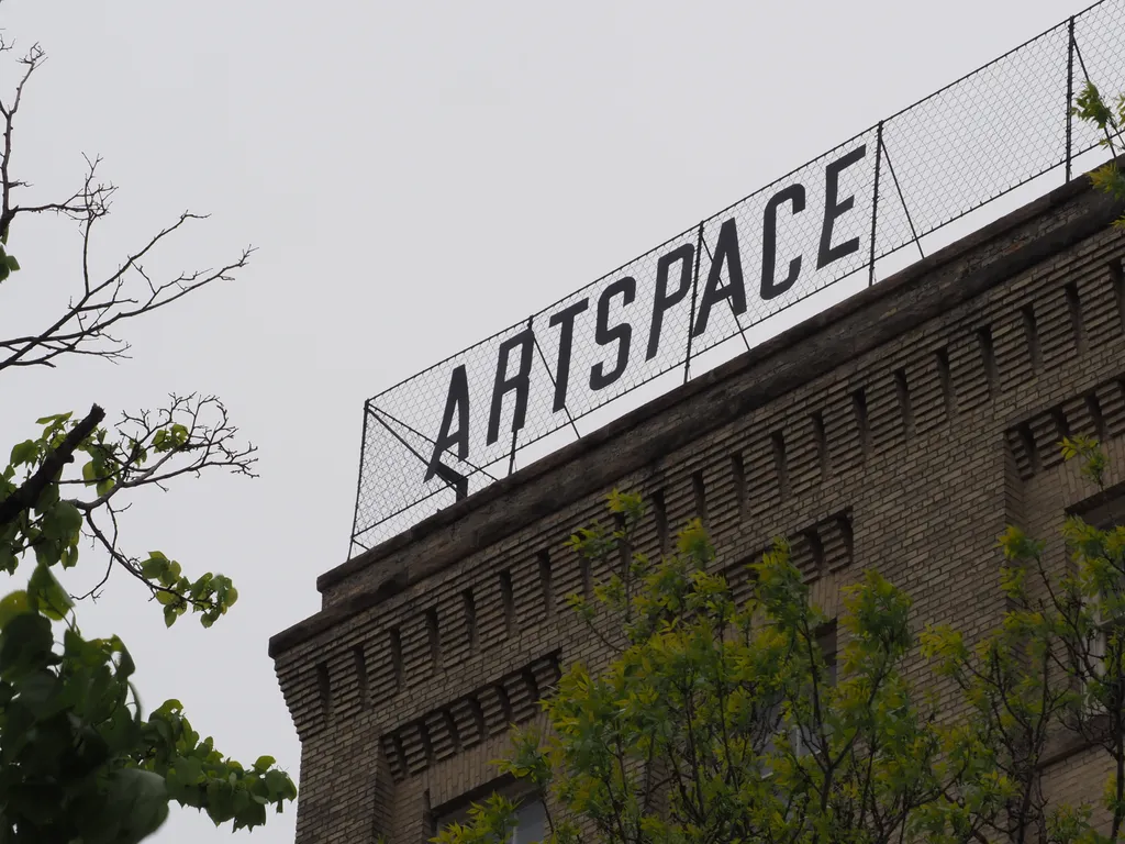 a sign on a tall brick building: artspce