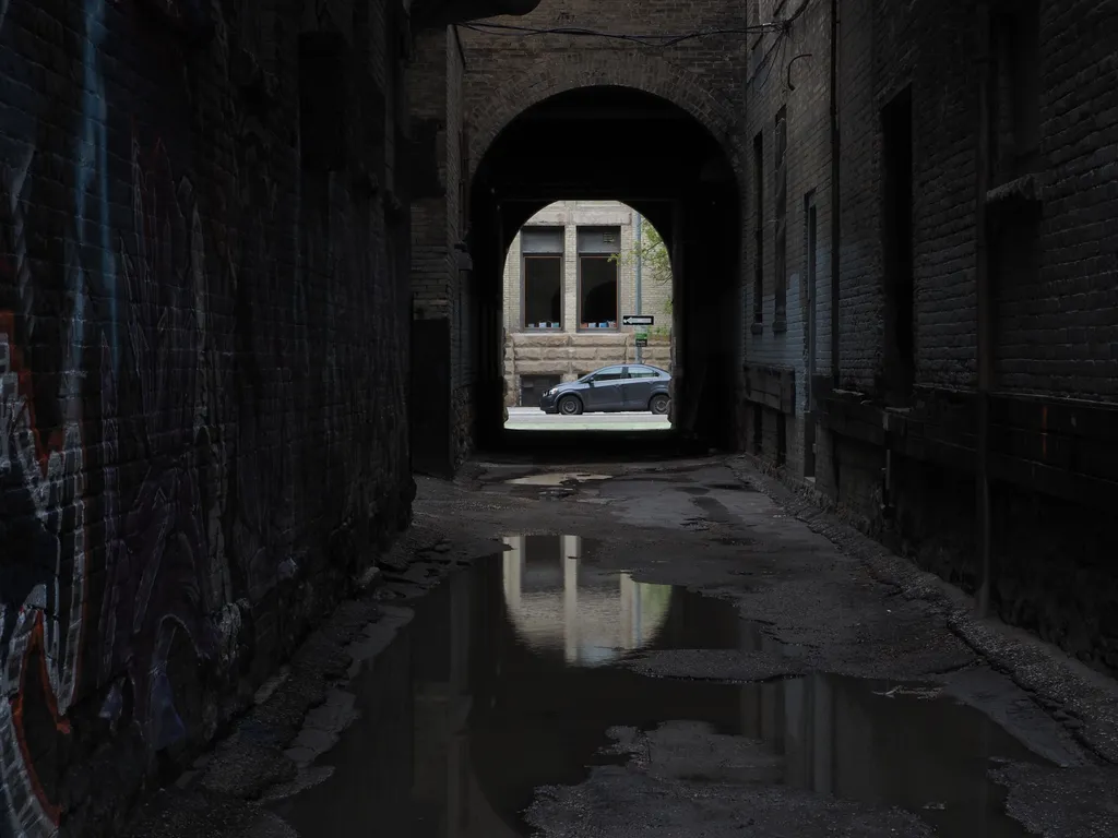 a puddle reflecting an arch in an alley