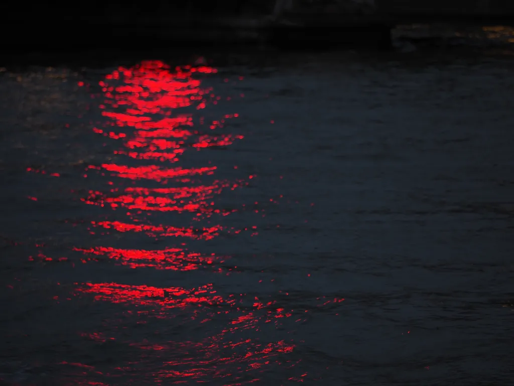 a red light reflecting on a swelling river at night