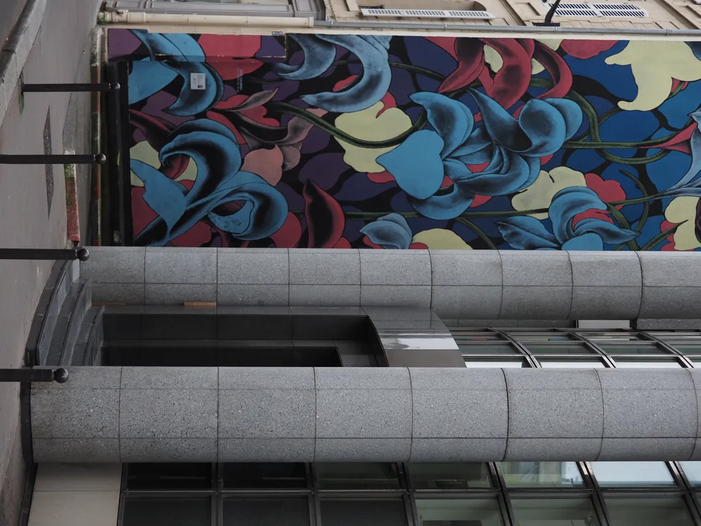 a floral mural beside stone pillars and a curved glass wall