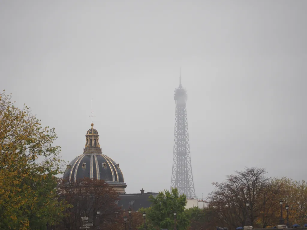 an ornate dome and the eiffel tower visible through the fog