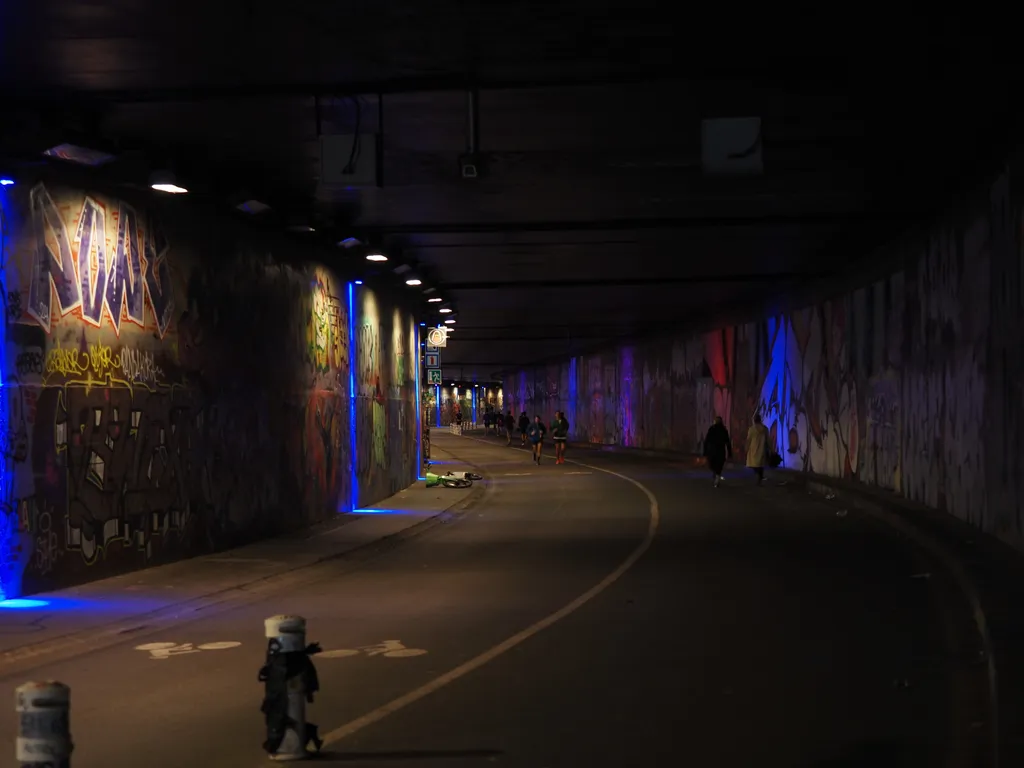 people walking along a graffiti-covered tunnel