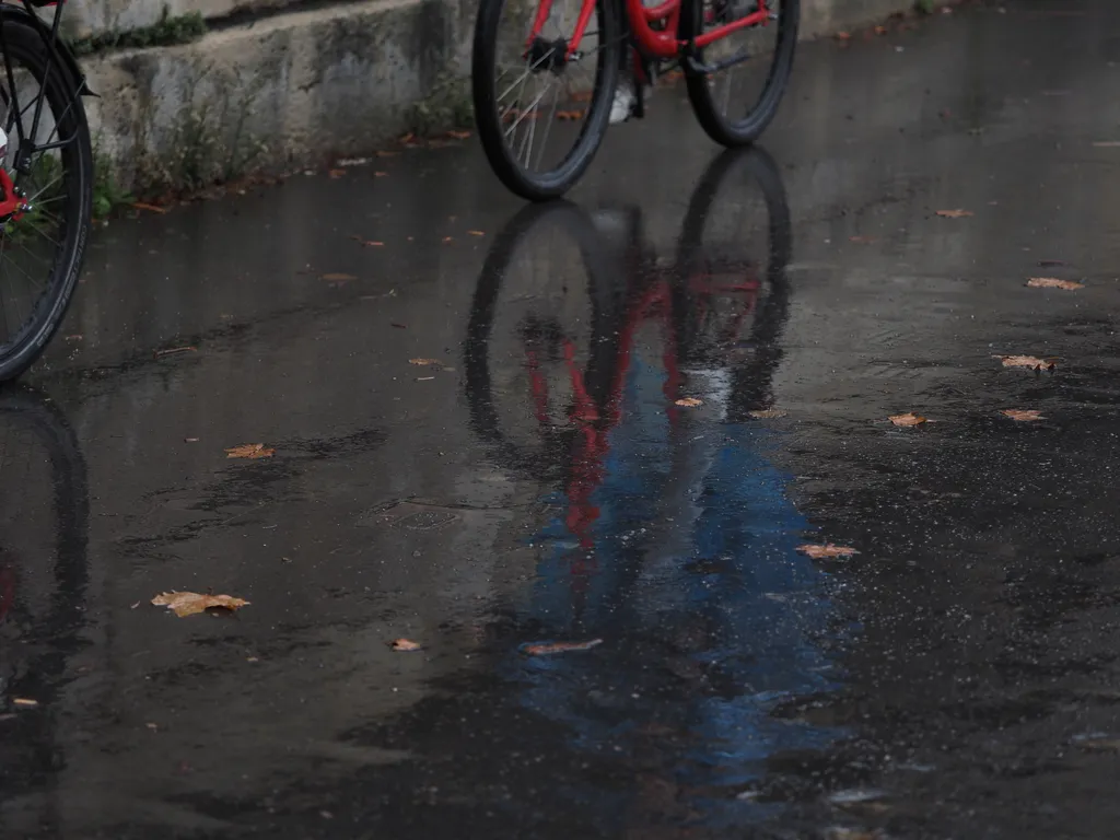 bikes reflected in a rainy sidewalk