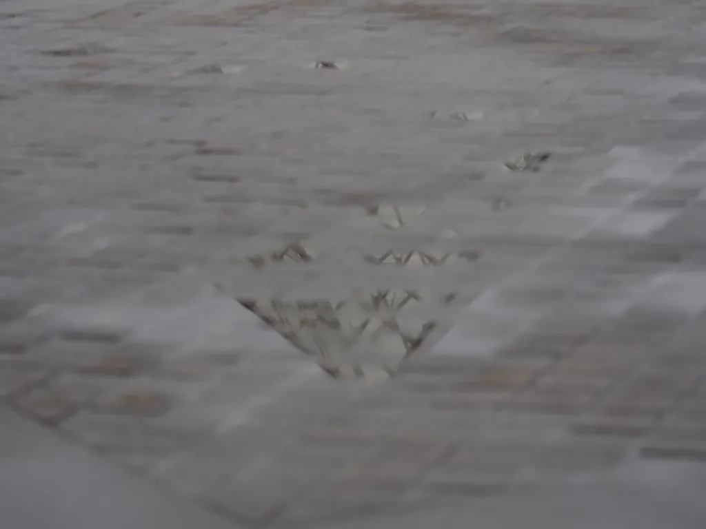 the glass pyramid of the louvre reflected in a puddle