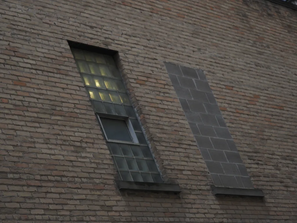 a window with glass blocks as panes beside a bricked up window