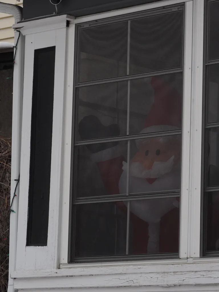 an inflatable santa waving through a window