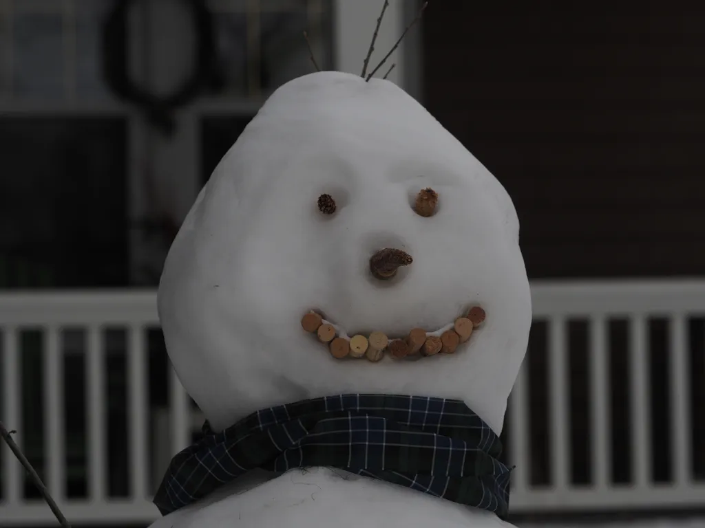 a snowman with a mouth made of wine corks and pinecone eyes